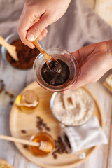 Concept of home beauty care ritual and natural organic ingredients in cosmetology. Woman making scrub with coffee, honey, oil, oat for gentle skin peeling and moisturizing. Health care lifestyle. 