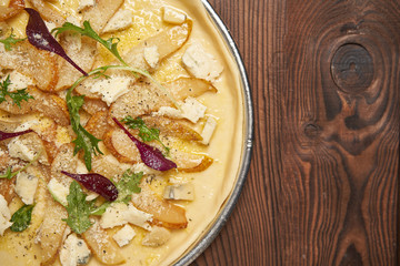 vegetarian raw pizza with gorgonzola cheese and pear on a metal plate ready to cook