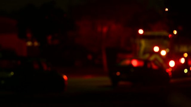 Blurred emergency ambulance or a paramedic fire truck on a crime scene or home front. Red warning lights flashing on the street at night. Giving medical attention at home or disaster or virus response