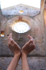 Hände in alter Kirche mit rundem Fenster
