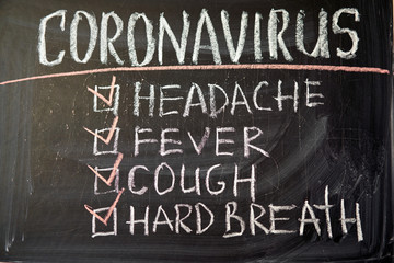 Coronavirus symptoms. Outbreak Warning. written white chalk on blackboard in connection with epidemic of coronavirus worldwide.