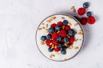Tasty fresh blueberry raspberries yoghurt shake dessert in ceramic bowl standing on white table background.
