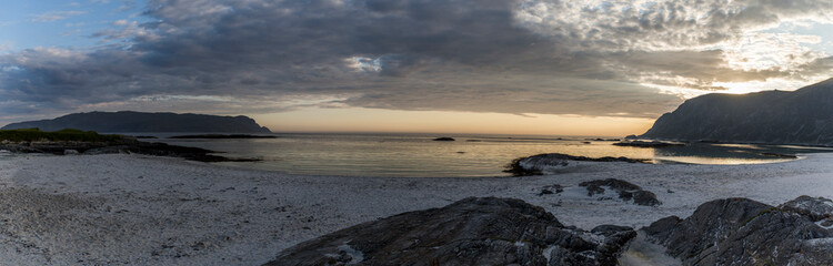 sunset on a stunning and deserted white sand beach, crystal clear water and green mountains