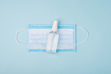Must have to prevent infection and protect yourself. Above overhead close up view photo of one medical mask and small bottle with antiseptic liquid isolated over pastel table background