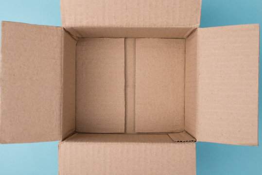 Top overhead above closeup view photo of unpacked empty box on blue background with blank copy space