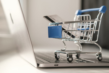 A mini trolley from a supermarket stands on a laptop keyboard. The concept of online shopping while quarantine 