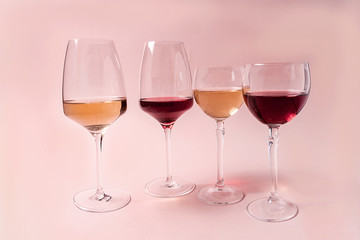 A set of rose and white wine in a glasses on pink background, front view.