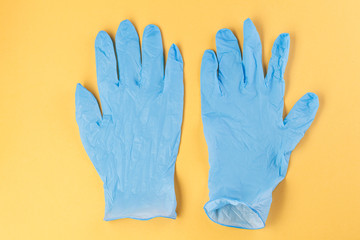 Fototapeta premium Two rubber gloves on a yellow background. Corona virus. Healthcare and medical concept. Close up view of medical protection of hands.