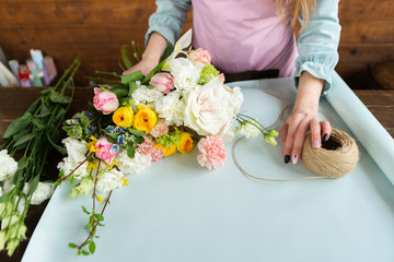 The concept of a flower shop . A female florist creates a flower arrangement on a wooden background. A beautiful bouquet of mixed flowers. Beautiful fresh bouquet. Flower delivery