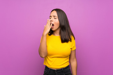 Young brunette girl over isolated background yawning and covering wide open mouth with hand