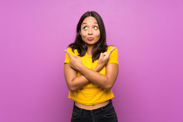 Young brunette girl over isolated background pointing to the laterals having doubts