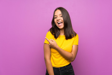 Young brunette girl over isolated background surprised and pointing side