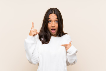 Young brunette woman with white sweater over isolated background with surprise facial expression