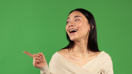 A young Asian-looking girl enthusiastically rejoices and raises her index fingers up