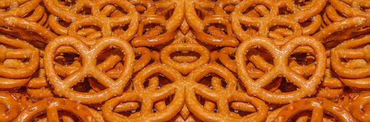 Salted Bavarian pretzel close-up, beer snack, banner. Mini pretzel, fresh baked goods. Background or texture of fresh baked pastry. Background of pretzels.	