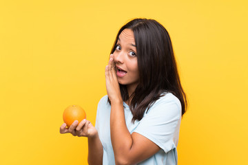 Fototapeta na wymiar Young brunette woman holding an orange whispering something