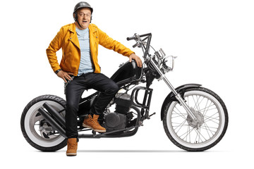 Obraz na płótnie Canvas Mature biker smiling and sitting on a chopper motorbike