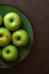 Green apples on a green plate.  Bright green apples on a green plate with a black rim against a...