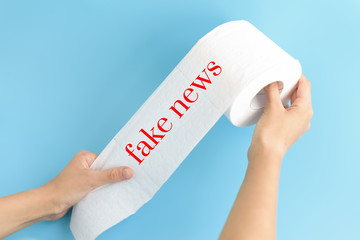 text fake news on white toilet paper on blue background, concept of lie in social media during coronavirus pandemic in the world