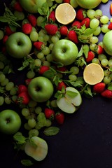 Fresh fruits including green apples, green grapes and red strawberries with lemon.  Portrait flat lay background.
