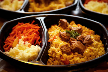 hot dish of meat and vegetables,with a side dish in a disposable container,for delivery of food at home