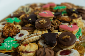 Some of Christmas cookies stored on a gold bowl of candy of different kinds of colors and shapes superimposed on each other on a white backgroun