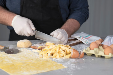 Obraz na płótnie Canvas Chef cutting a roll of pasta into noodles