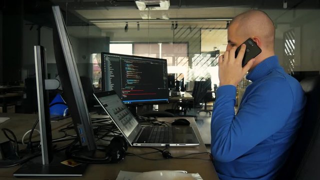 The programmer works at a computer in an empty office during quarantine. Working from home