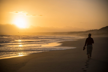 Fototapeta na wymiar silhouette of a woman walking on the beach at sunset