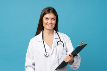 Young woman over isolated blue background with doctor gown and holding a folder