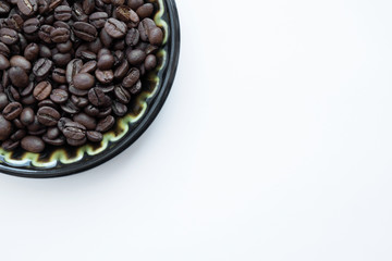 Natural coffee beans on a plate, nk white background. View from above.