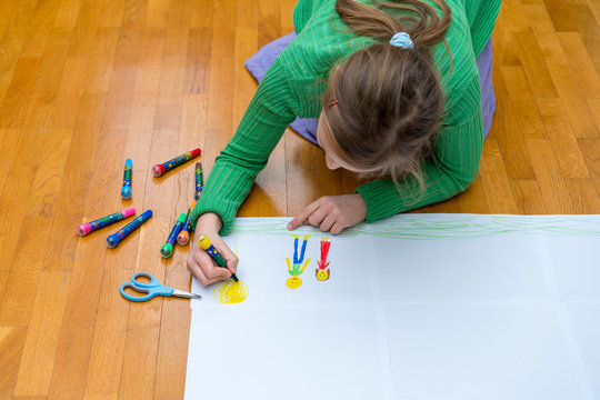 Adorable little girl drawing artwork top view on floor, Baby healthy and school concept. girl lying on floor painting with colored marker. Lovely multiethnic child drawing. toned