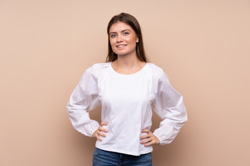 Young girl over isolated background posing with arms at hip and smiling