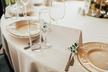 Invitation near a plate with copy space. White plate on a pastel tablecloth. Beautiful table decoration for wedding party. Table setting.