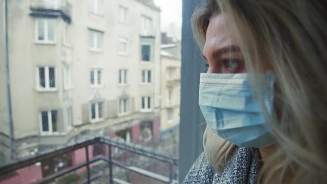 Profile of exhausted sick young woman in white protection mask staying at home taking care on isolation period. Spread of coronavirus. Pandemic concept.