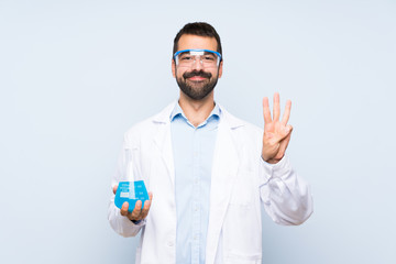 Young scientific holding laboratory flask over isolated background happy and counting three with fingers