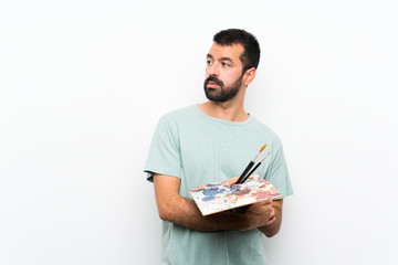 Young artist man holding a palette over isolated background portrait