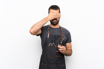 Barber man in an apron covering eyes by hands. Do not want to see something