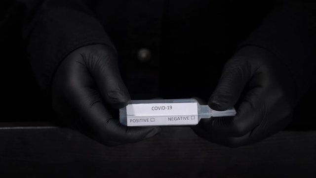 Closeup of microbiologist or medical worker hand with black surgical gloves new rapidly spreading Coronavirus. COVID-19 
