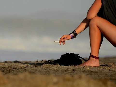 Persona fumando en la playa