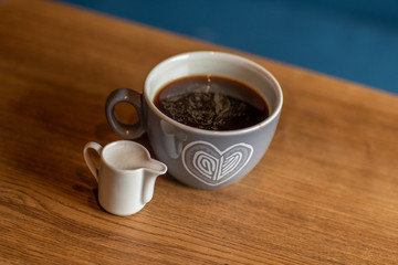 a cup of coffee is on a wooden table with a cup of milk. blue background. Top view