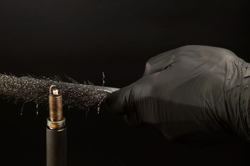 Cleaning the spark plug thread with a wire brush. Internal combustion engine service.