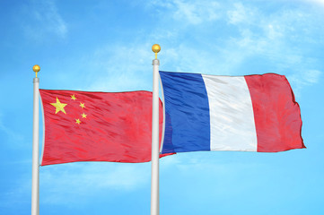 China and France two flags on flagpoles and blue cloudy sky