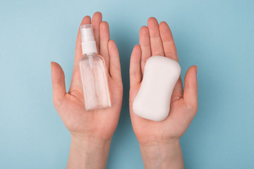Pov top above overhead closeup view photo of woman making a choice between two products holding on hands soap and transparent antiseptic isolated over blue background