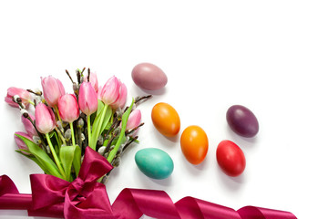 Obraz premium Easter background with pink tulips tied with a ribbon, catkins and colorful Easter eggs