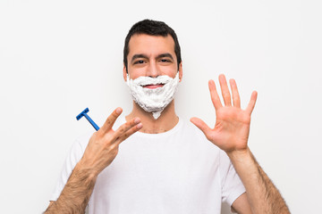 Man shaving his beard over isolated white background counting eight with fingers