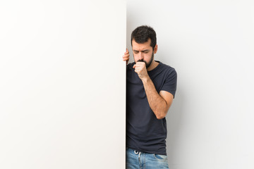 Young handsome man with beard holding a big empty placard is suffering with cough and feeling bad