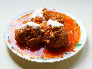 Minced meat meatballs with rice in sauce, sprinkled with sour cream.