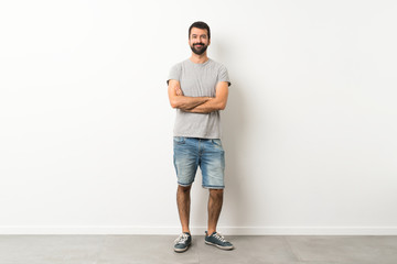 A full-length shot of handsome man with beard keeping the arms crossed in frontal position