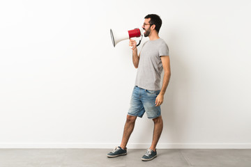A full-length shot of handsome man with beard shouting through a megaphone
